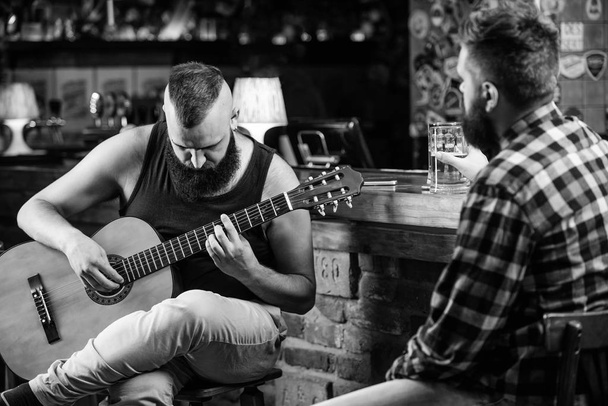 Friends relaxing in bar or pub. Hipster brutal bearded spend leisure with friend in bar. Real men leisure. Cheerful friends relax with guitar music. Man play guitar in bar. Friday relaxation in bar - Fotografie, Obrázek