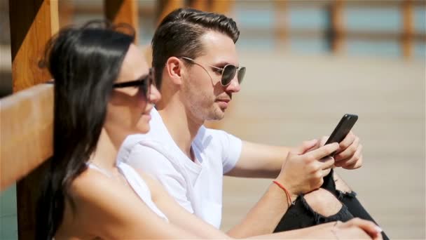 Obrázek radostného páru používajícího smartphony v parku - Záběry, video