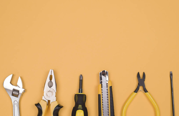 Zwart geel tools-mes, tangen, meetlint, schroevendraaier, Nippers op een gele achtergrond. Plaats voor tekst. Werkvoorraad - Foto, afbeelding