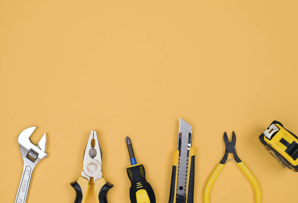 Μαύρα κίτρινα εργαλεία-μαχαίρι, πένσα, μεζούρα, κατσαβίδι, σταγόνες σε κίτρινο φόντο. Θέση για κείμενο. Απογραφή εργασίας - Φωτογραφία, εικόνα