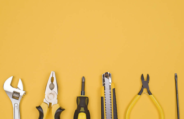 Black yellow tools - knife, pliers, tape measure, screwdriver, nippers on a yellow background. Place for text. Work inventory - Foto, Bild