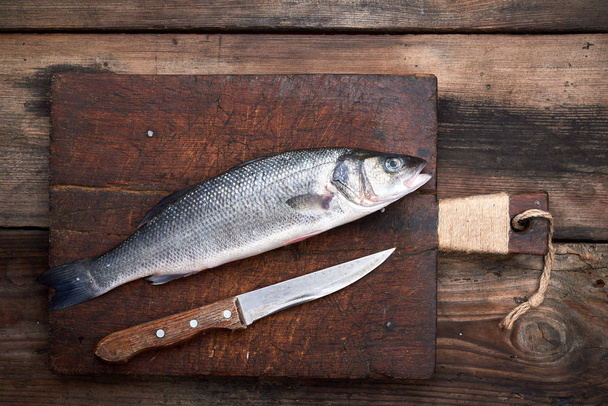 fresh whole sea bass fish on brown cutting board  - Foto, immagini