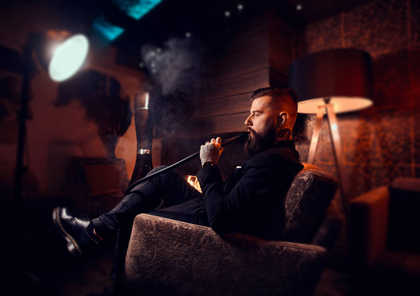 Elegante homem inteligente é relaxante e fumar narguilé depois de longo dia difícil
 - Foto, Imagem