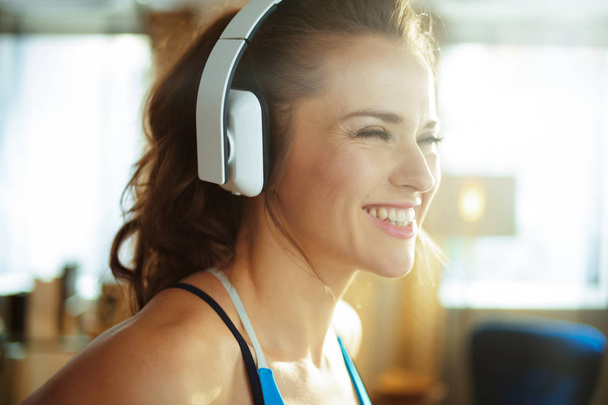 sports woman listening to music with headphones in modern house - Photo, Image