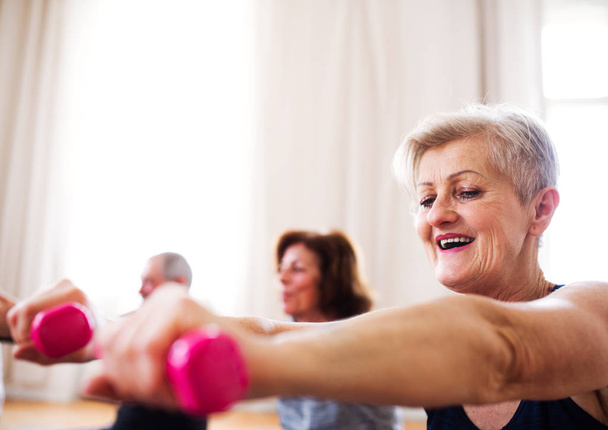 Grupo de personas mayores haciendo ejercicio con pesas en club de centro comunitario
. - Foto, Imagen
