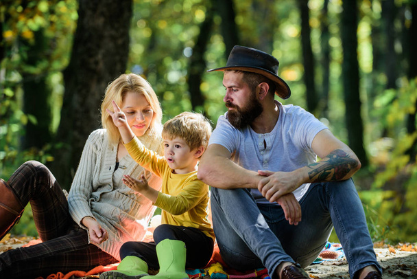 Mom dad and kid boy relaxing while hiking in forest. Family picnic. Mother father and little son sit forest picnic. Good day for spring picnic in nature. Explore nature together. Family day concept - Fotografie, Obrázek