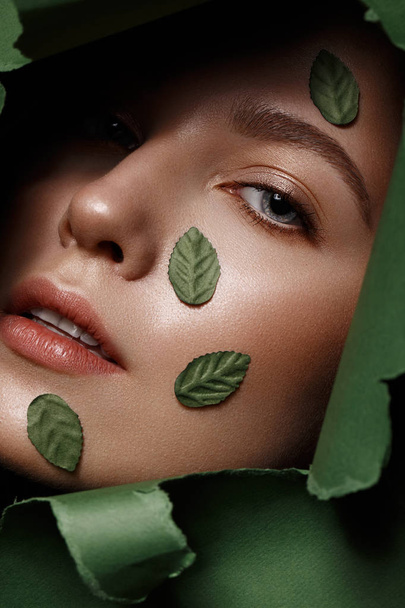 Beautiful fresh girl with perfect skin, natural make up and green leaves. Beauty face. Close up - Photo, image