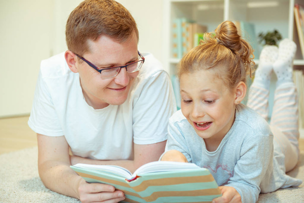 Young happy father reading book with  cute daughter at home - Foto, imagen