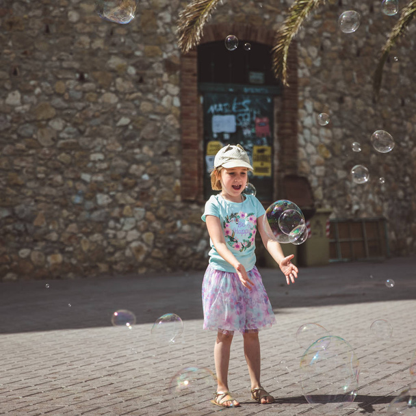 Pretty Little Girl gra z dużymi bąbelkami w ulicy w letni dzień - Zdjęcie, obraz