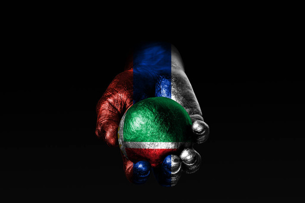 Uma mão com uma bandeira russa hasteada segura uma bola com uma bandeira da Chechênia hasteada, um sinal de influência, pressão ou conservação e proteção
. - Foto, Imagem