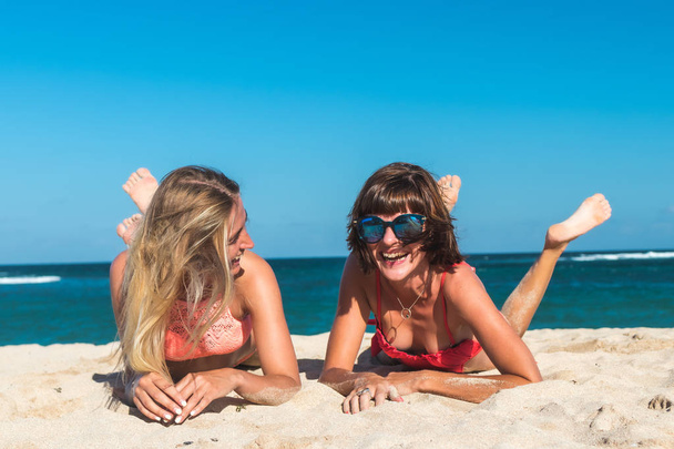 Δύο γυναίκες ηλιοθεραπεία ξαπλωμένοι στην τροπική παραλία καλοκαίρι ταξίδια διακοπές. Μπαλί. - Φωτογραφία, εικόνα