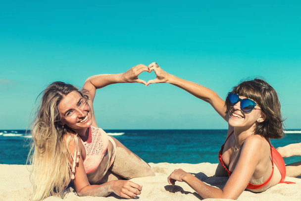zwei Frauen sonnen sich im Liegen am tropischen Strand im Sommerreiseurlaub. bali-Insel. - Foto, Bild