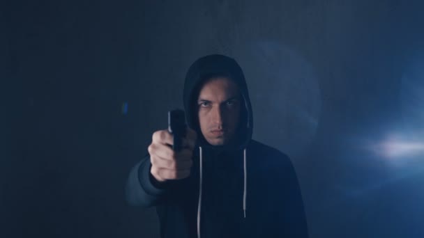Perigoso encapuzado criminoso aponta sua arma no fundo preto
 - Filmagem, Vídeo