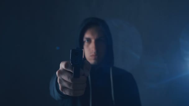 Peligroso encapuchado Criminal apunta su pistola sobre fondo negro
 - Metraje, vídeo
