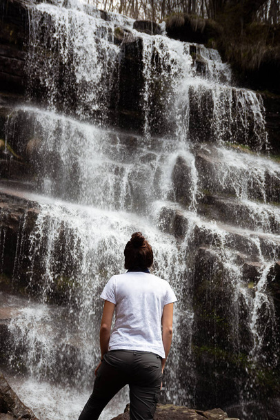 Girl standing in front of a waterfall - Fotoğraf, Görsel