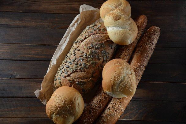 Αρτοποιείο. Φρέσκο αρωματικό ψημένο ψωμί. Σπιτικό ψωμί σε ξύλινο φόντο - Φωτογραφία, εικόνα