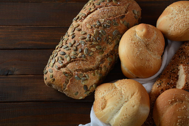 Bakery. Fresh fragrant baked bread. Homemade bread on wooden background - Photo, Image