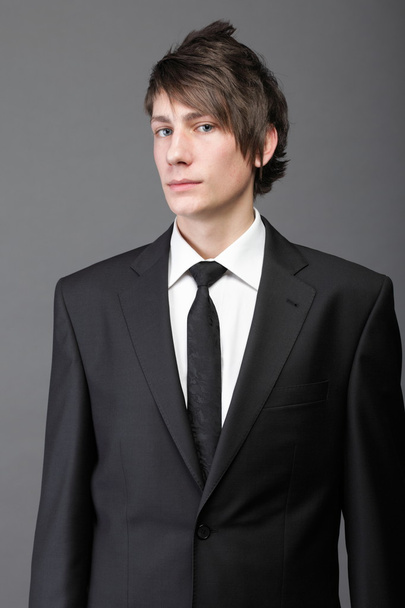 young businessman black suit casual tie on gray background - Фото, зображення