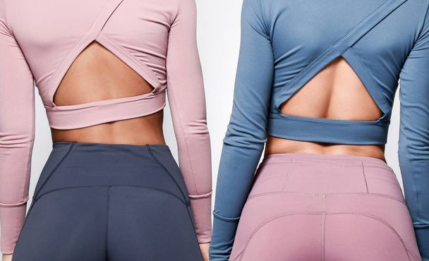 Two girls in athletic body cloth sport wear pants blue and pink on gray - Fotografie, Obrázek