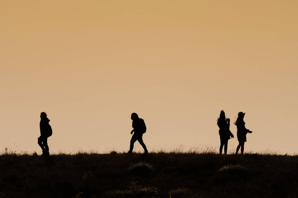 Silhouetten van wandelliefhebbers met rugzakken genieten van zonsondergang vanaf t - Foto, afbeelding