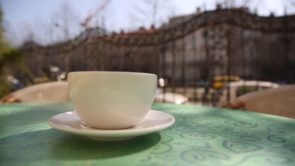 heiße Kaffeetasse mit Dampf auf dem Tisch im Café am Morgen, draußen - Filmmaterial, Video
