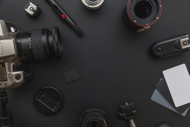 Lugar de trabajo del fotógrafo con sistema de cámara dslr, kit de limpieza de la cámara, lente y accesorio de la cámara sobre fondo de mesa negro oscuro
 - Foto, Imagen