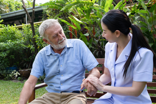 Senior man geluk zittend met lachende verpleegster, neemt zorg en  - Foto, afbeelding
