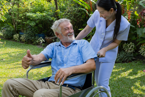 starszy mężczyzna szczęście siedzi na wózku inwalidzkim z uśmiechniętą pielęgniarką, t - Zdjęcie, obraz