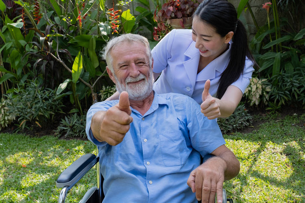 ανώτερος άνθρωπος ευτυχία κάθεται σε αναπηρικό αμαξίδιο με χαμογελαστή νοσοκόμα, t - Φωτογραφία, εικόνα