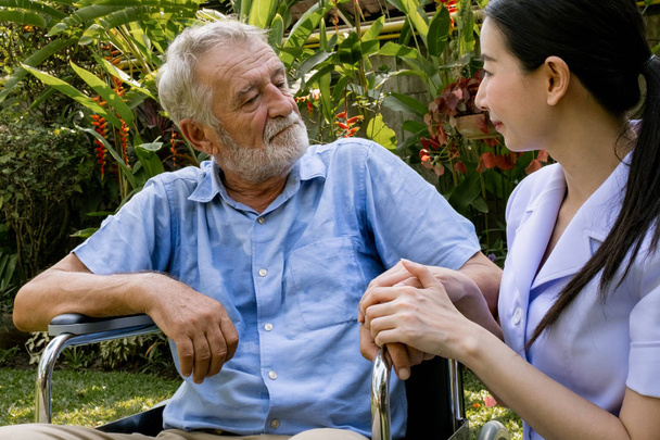 Starší člověk štěstí sedí na vozíku s usměvavou ošetřovatelkou, t - Fotografie, Obrázek