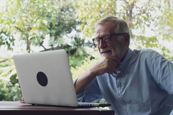 Senior man sitting and happy for using laptop at balcony near ga
 - Фото, изображение