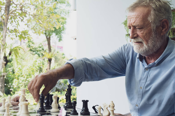 hombre mayor jugando ajedrez en balcón cerca del jardín en el hogar de ancianos
  - Foto, Imagen