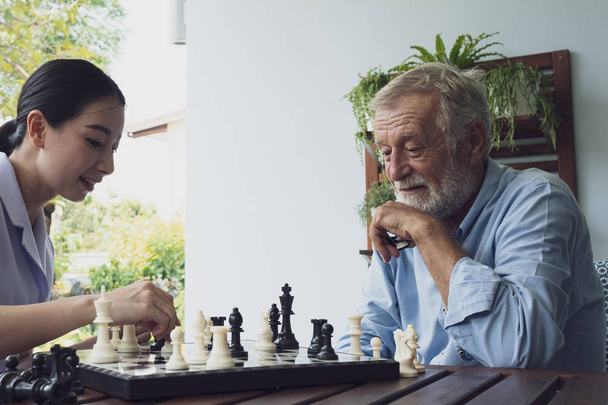 anciano felicidad hombre y enfermera, jugando ajedrez en balcón cerca ga
 - Foto, Imagen