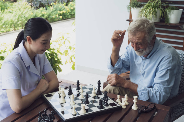 anciano felicidad hombre y enfermera, jugando ajedrez en balcón cerca ga
 - Foto, Imagen