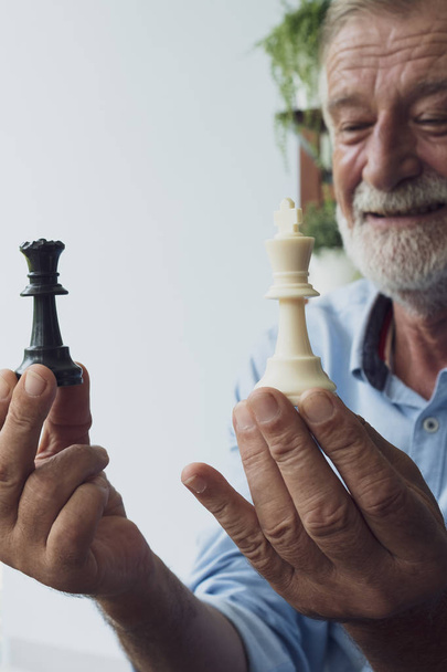 Senior Man boldogság gondolkodás és a sakkozás az erkélyen közelében  - Fotó, kép