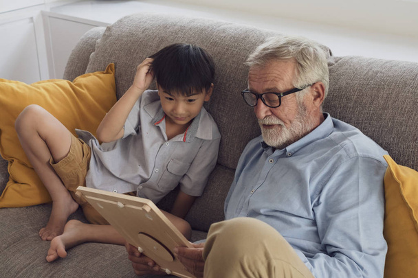 hombre mayor felicidad y nieto están sentados en el sofá y pl
 - Foto, Imagen