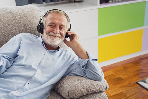 starszy człowiek szczęście siedzi na kanapie i słuchanie muzyki WIT - Zdjęcie, obraz