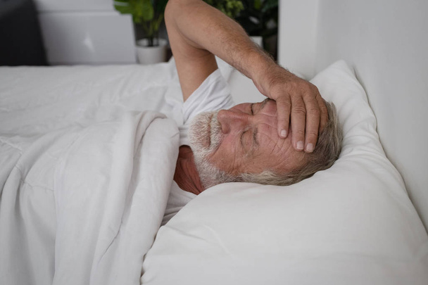 一人で寝ているシニア男性と頭痛や夢の悪夢  - 写真・画像
