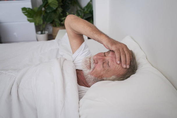 starszy mężczyzna śpi samotnie i ból głowy lub marzy koszmar na  - Zdjęcie, obraz