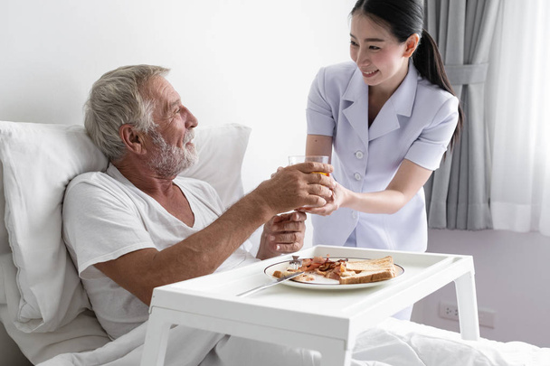 vanhempi mies hymyilevä sairaanhoitaja, hoitaa aamiaisen ja keskustelee
 - Valokuva, kuva