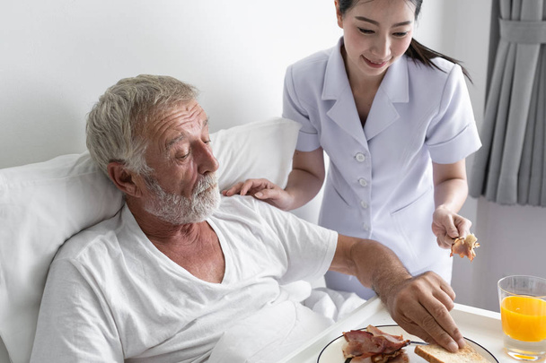 anciano con enfermera sonriente, toma el desayuno cuidado y discutir
 - Foto, Imagen