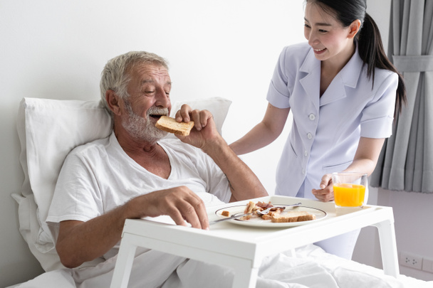 starší muž s usměvavou ošetřovatelkou, pečuje o snídani a discussi - Fotografie, Obrázek