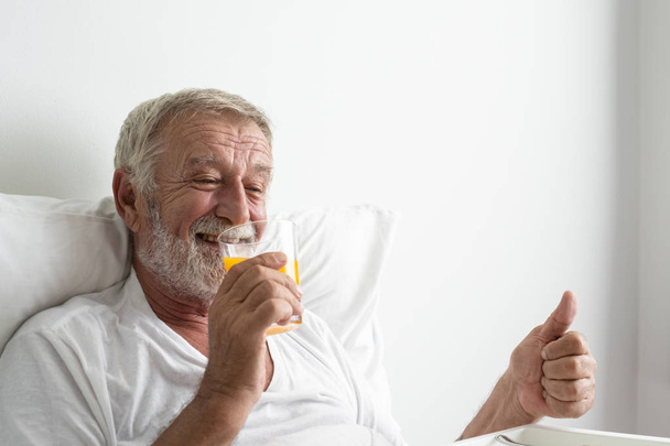 idősebb férfi mosolyogva és puffanás fel felvidítani ágyon az ápolási Hom - Fotó, kép