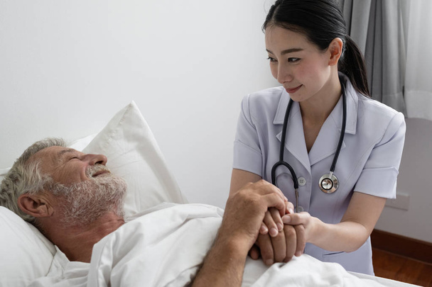 старший мужчина с улыбающейся медсестрой, заботится и болеть на кровати на ню
 - Фото, изображение
