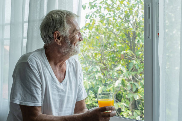 senior man hold glass of orange juice and thinking and looking o - Φωτογραφία, εικόνα