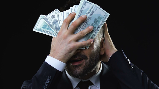 Hombre de negocios codicioso acariciando la cara con billetes de dólares, disfrutando de la riqueza
 - Metraje, vídeo