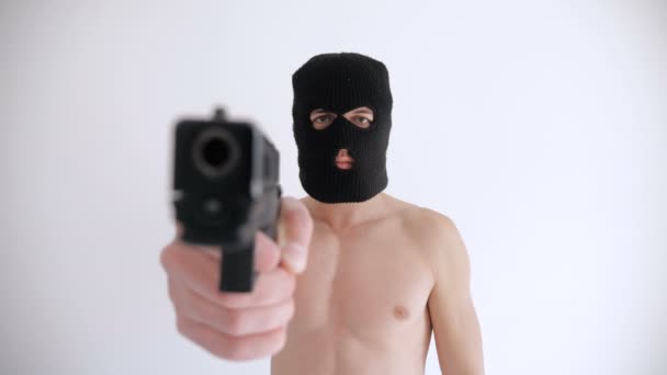 Террорист с обнаженным туловищем в балаклаве целится из пистолета на белом фоне
 - Кадры, видео