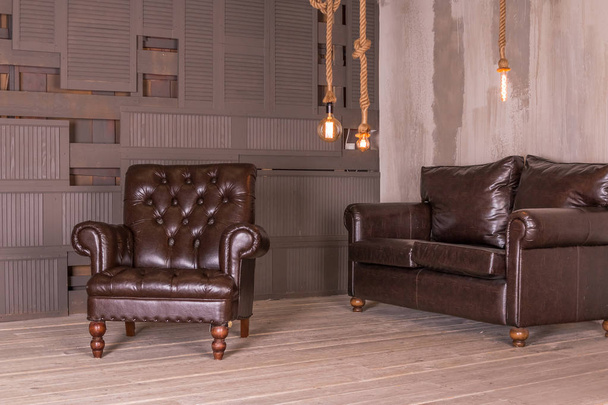 Καφέ δερμάτινη πολυθρόνα και εκλεκτής ποιότητας δερμάτινο καναπέ. εσωτερική σύνθεση. Δημιουργικός σχεδιασμός. Αντιγραφή χώρου - Φωτογραφία, εικόνα