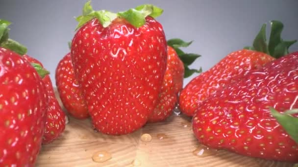 Μια κούκλα από κόκκινες ζουμερές φράουλες σε ξύλινο φόντο. Γλυκιά συγκομιδή φράουλα φόντο, υγιής τρόπος ζωής του φαγητού - Πλάνα, βίντεο