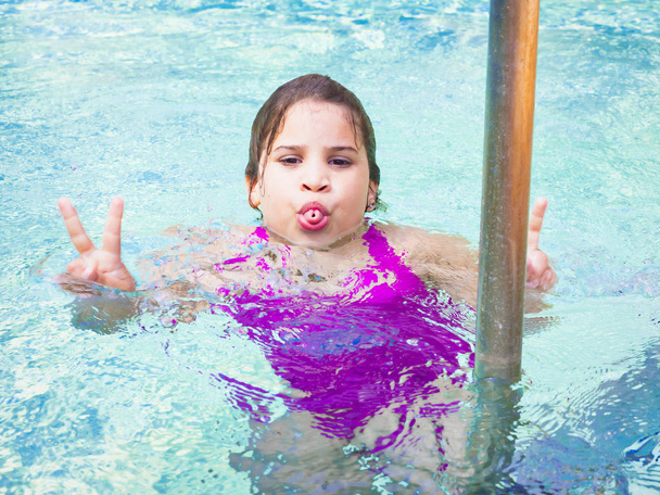 persone, gesti e adolescenti concetto felice sorridente bella ragazza adolescente che mostra segno di pace su sfondo blu acqua, in piscina
 - Foto, immagini